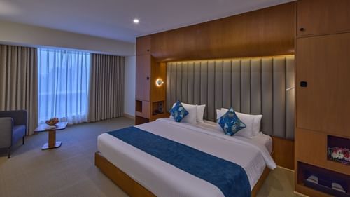 a double bed and a sofa with a coffee table in The Grand Premier King Sea View at Grand Continent, Mahabalipuram